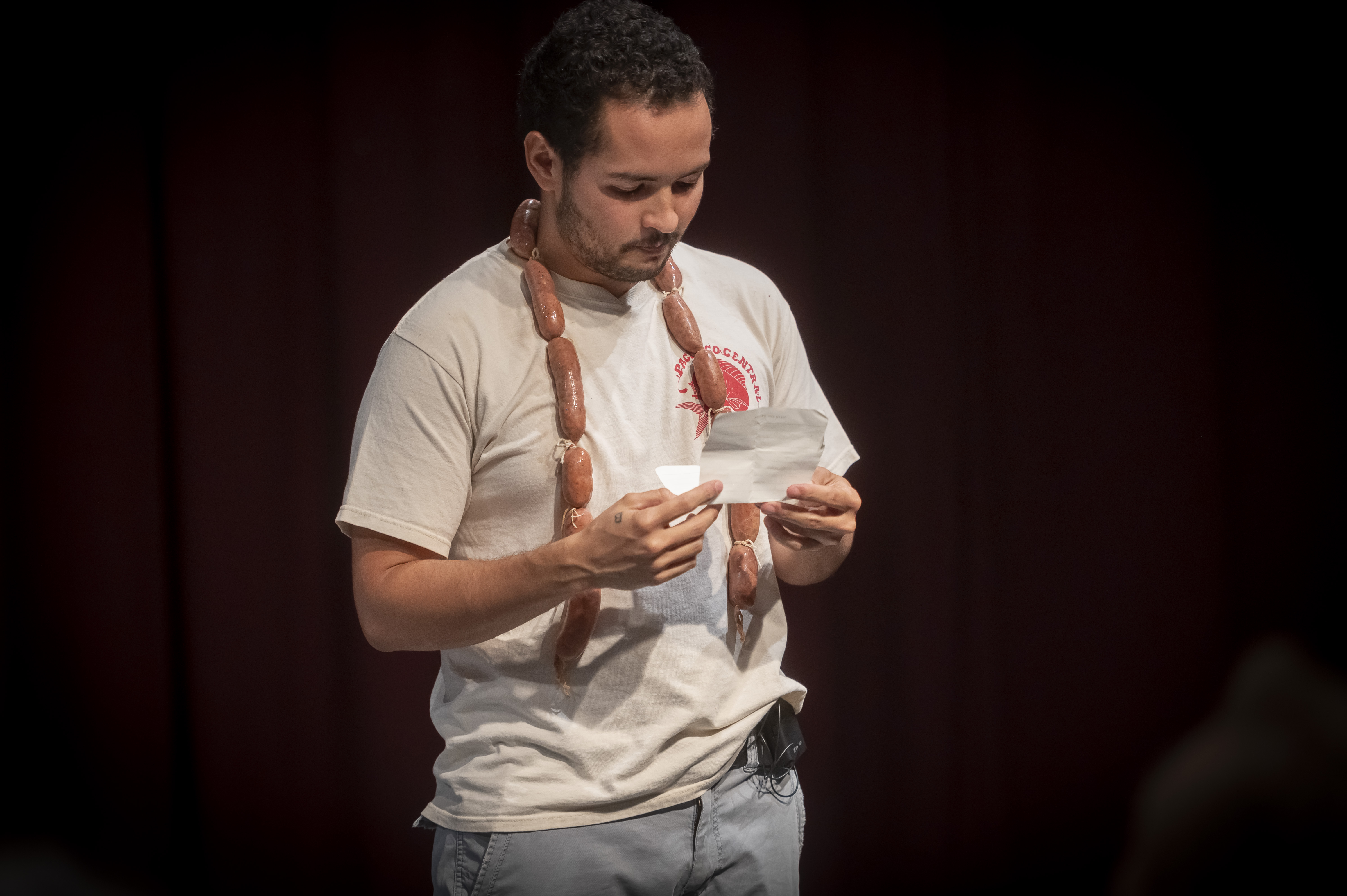 Un joven con un collar de chorizos lee una carta.